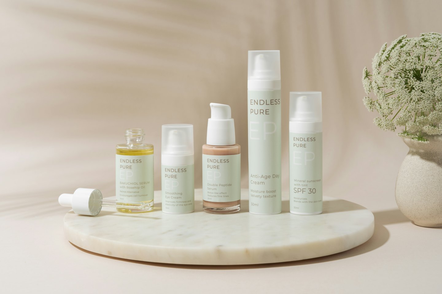 Skincare products arranged on a white marble tray with flowers.