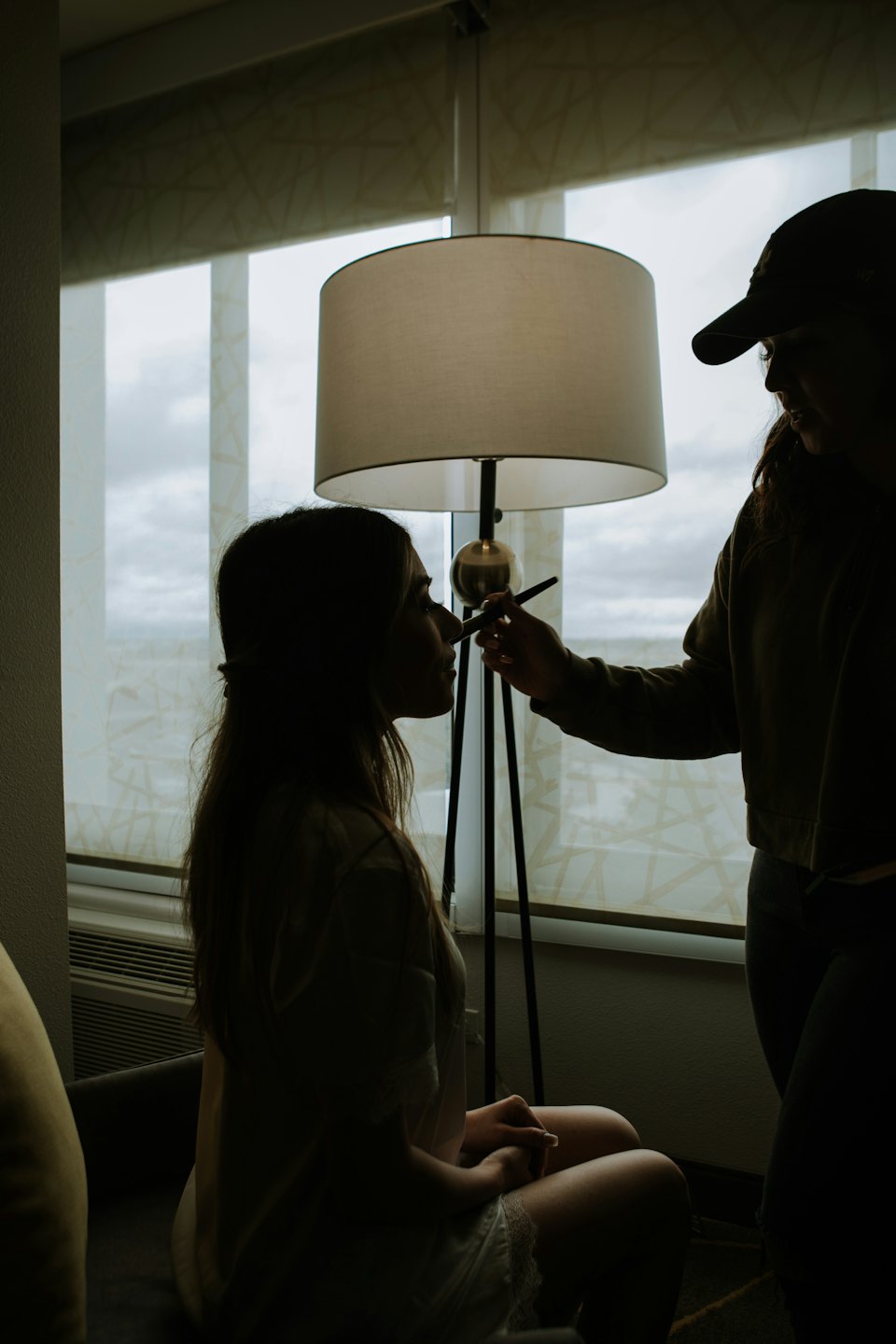 Makeup artist applying makeup to client's face in silhouette.
